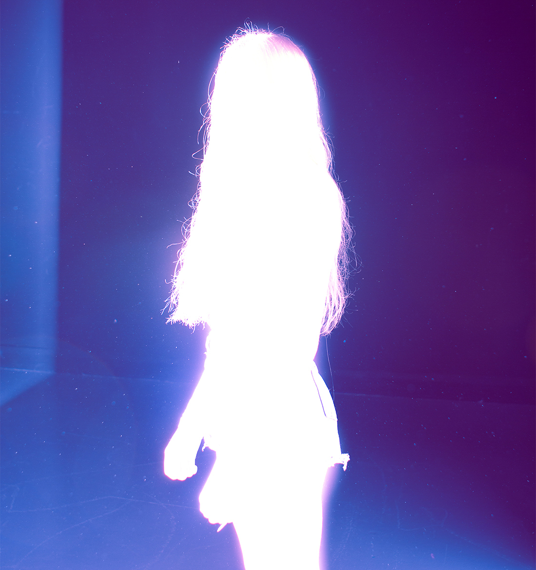 A purple image with a white glowing figure standing still.